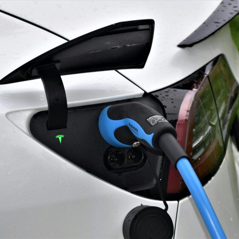 Ein Elektroauto beim Laden mit einem blauen Ladekabel.